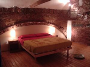 een slaapkamer met een bed in een bakstenen muur bij Amenano Apartments in Catania