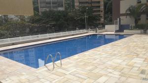 a large swimming pool with blue water in a building at Pitangueiras 3 suítes com vista para o mar in Guarujá