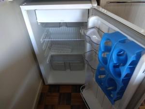 um frigorífico aberto com um par de utensílios azuis em Soratur Hotel & Coworking em Criciúma