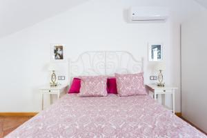 1 dormitorio con 1 cama grande con almohadas rosas en EDEN RENTALS Duplex Adeje Palace en Playa Paraiso