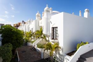 a white building with palm trees in front of it at EDEN RENTALS Duplex Adeje Palace in Playa Paraiso
