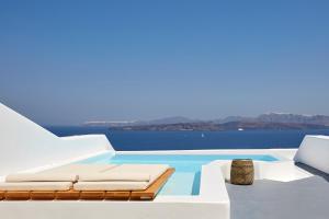 a pool on the side of a house with white furniture at Phos The Boutique in Akrotiri