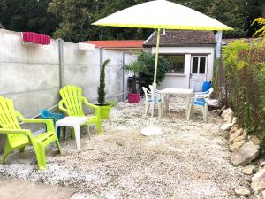 un patio con sillas, una mesa y una sombrilla en maison Vendeuvre sur barse, en Vendeuvre-sur-Barse