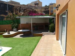 einen Garten mit einer Terrasse und Gras in der Unterkunft Vivienda Unifamiliar Sela in Santa Cruz de Tenerife