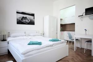a white bedroom with a white bed and a kitchen at City Castle Aparthotel in Prague
