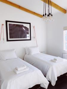 two beds in a white room with white sheets at Hotel Boutique El Establo in Puerto Natales