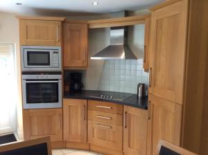 una cucina con mobili in legno e un forno a piano cottura di Craig Cottage a Banff