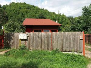 a wooden fence with a house behind a wooden fence at Canadian House in Sărata-Monteoru
