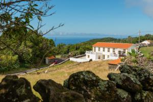 a house on a hill with the ocean in the background at Casa da Figueirinha in Calheta de Nesquim