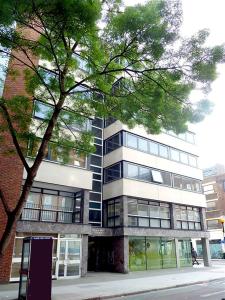 un edificio alto con un árbol delante de él en Superb 3-Bed 2-Bath with Wifi: Trendy Fitzrovia W1 en Londres