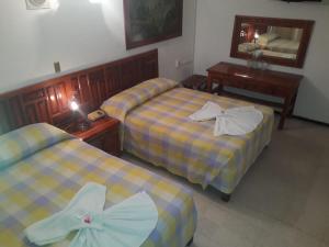 a hotel room with two beds and a mirror at Hotel Maria Luisa in Iguala de la Independencia