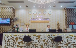 Dos personas sentadas en el mostrador de recepción del hotel Agas en A25 Hotel - 19 Phan Đình Phùng, en Hanói