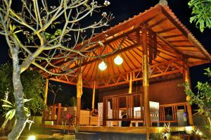 a house with a wooden roof at night at Setilas Bungalows in Nusa Penida