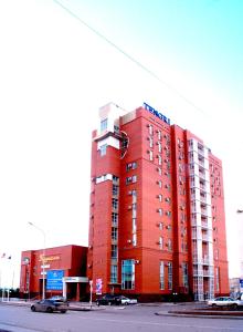 un bâtiment rouge avec des voitures garées devant lui dans l'établissement Tengri Hotel, à Astana