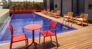 eine Terrasse mit Stühlen, Tischen und einem Pool in der Unterkunft The B Hotel Quezon City in Manila