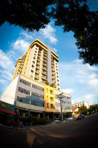 un edificio alto amarillo y blanco en una calle en Aquarius Hotel Flat Residence en Santa Cruz do Sul