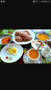 stół z talerzami jedzenia i kubkami kawy w obiekcie Minara Guest House w mieście Mirissa