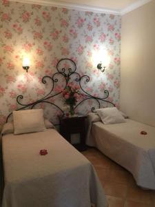 two beds in a room with flowers on the wall at Hotel Rural Andalucia in Sierra de Yeguas