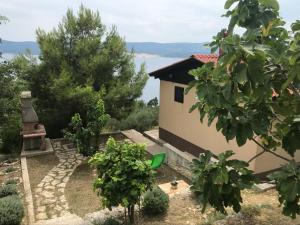 a house with a garden with trees in front of it at Charismatic Garden Cottage with Sea View in Lokva Rogoznica