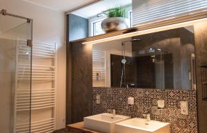 a bathroom with two sinks and a mirror at StrandBerg's Auberge Chalet Residences in Braunlage