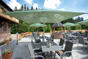 un patio avec des tables et des chaises sous un parasol vert dans l'établissement Landgasthof Sonne, à Alpirsbach