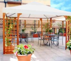 patio ze stołami i krzesłami oraz białym parasolem w obiekcie Hotel Cassia w Rzymie