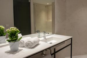 a bathroom with a sink and a mirror and towels at MH Apartments Central Madrid in Madrid