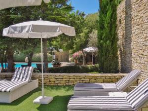 two chairs and an umbrella next to a pool at Le Jas de Gordes in Gordes