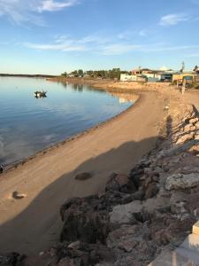 a beach with a boat in the water at Beachside & Jetty View Apartment 6 - Captain's Apt in Streaky Bay