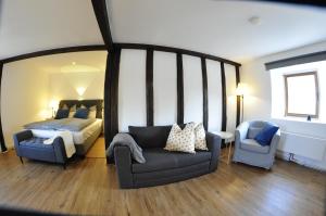 ein Schlafzimmer mit einem Bett, einem Sofa und einem Stuhl in der Unterkunft Pension Schwedenkreuz in Reimerath