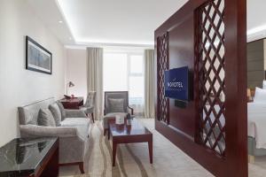 a hotel room with a king sized bed and a living room at Novotel Ulaanbaatar in Ulaanbaatar