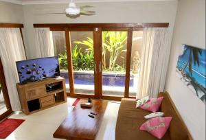 a living room with a couch and a flat screen tv at Villa Anyelir in Seminyak