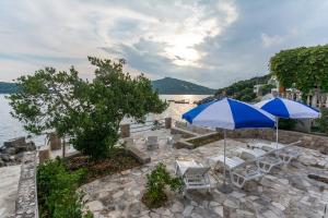 een groep stoelen en parasols op een patio aan het water bij Villa Molunat in Molunat