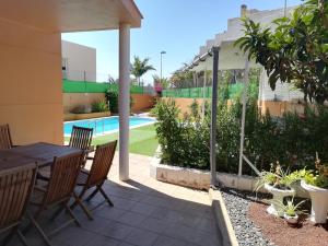 een patio met een tafel en stoelen en een zwembad bij Vivienda Unifamiliar Sela in Santa Cruz de Tenerife