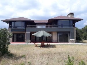 a house with a table and an umbrella in front of it at Ol Pejeta Holiday Villas in Nanyuki