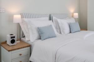 a white bed with white pillows and a night stand with a clock at Sea Breeze Cottage with Parking in Brighton & Hove