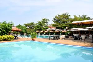 a swimming pool with tables and chairs and umbrellas at Hotel Club du Lac Tanganyika in Bujumbura