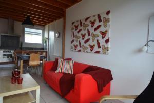 een woonkamer met een rode bank en een keuken bij Roche Blanche 1 in Saint-Lunaire