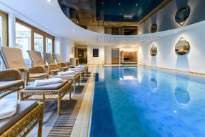 a hotel pool with chairs and a swimming pool at Staudacherhof in Garmisch-Partenkirchen I Blick aufs Zugspitzmassiv I einzigartige Bayurvida Küche in Garmisch-Partenkirchen