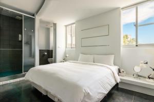 ein weißes Schlafzimmer mit einem großen Bett und einer Dusche in der Unterkunft Modena B&B in Taitung