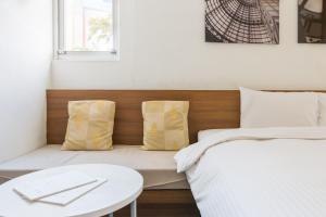 a bed with two pillows and a table in a room at Modena B&B in Taitung City