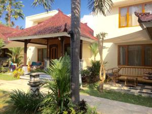 a house with a palm tree in front of it at Astina Hotel in Lovina