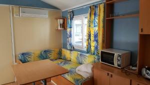 un soggiorno con divano e microonde di Mipro Mobilhome a Lido di Spina