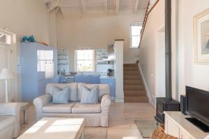 a living room with a couch and a tv at The Majestic Apartments in Kalk Bay