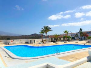 a large swimming pool with palm trees and buildings at New renovated duplex near the ocean located in Tenerife Sur in Costa Del Silencio