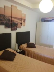 a bedroom with two beds and a painting on the wall at El Peñoncillo in Torrox +11 photos