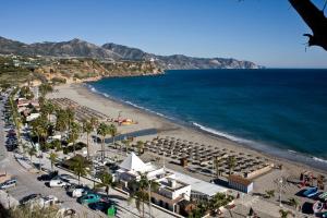 a beach with a lot of umbrellas and the ocean at El Peñoncillo in Torrox