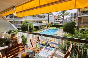 a balcony with a table and chairs and a pool at Beachfront Resort Apartment in Castelldefels