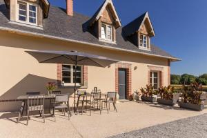 a patio with chairs and an umbrella in front of a house at Chambres "Le Tirel " in Reux