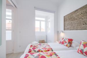 a white bedroom with a bed and a large window at Santiago Center Rooms in Santiago de Compostela